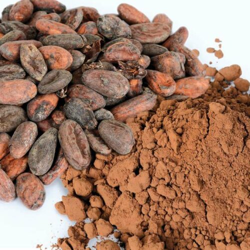 Kakaobohnen liegen neben klumigem Kakaopulver
