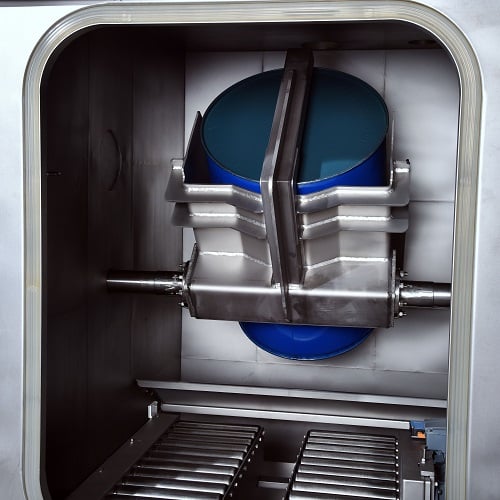 Ein blaues Industriefass welches vollautomatisch in einer geöffneten Entleerkabine kopfüber entleert wird.
