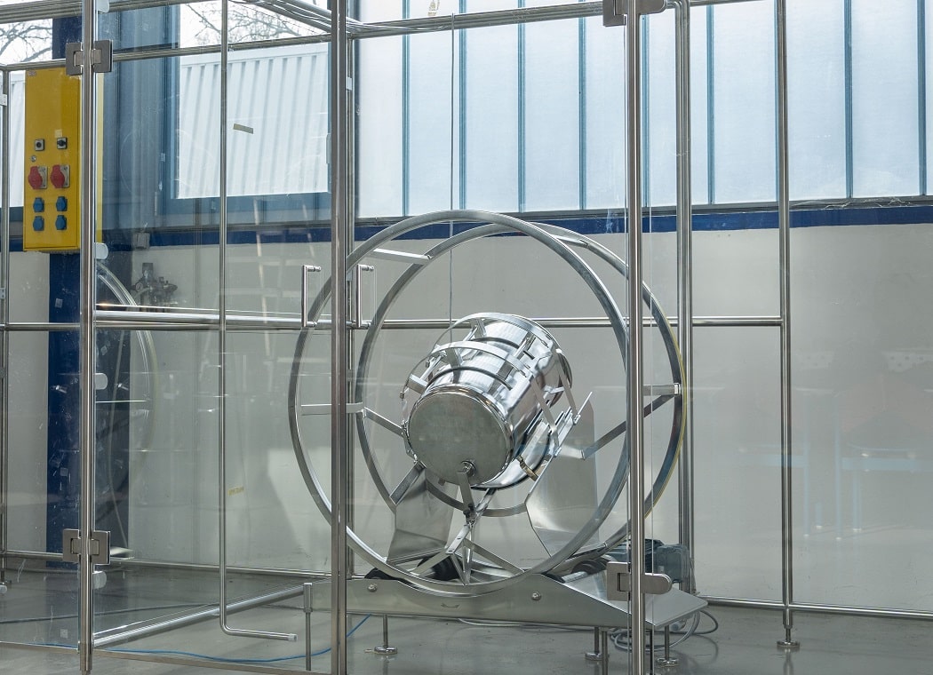 Mischbehälter aus Edelstahl im Rhönradgestell des JEL RRM, das von einer Schutzumwehrung aus Glas umgeben ist.